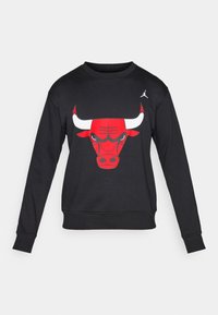 Melns krekls ar garām piedurknēm, uz kura priekšpuses ir liels sarkans Chicago Bulls logo. Uz pleca ir iekļauts arī balts Jordan logo.