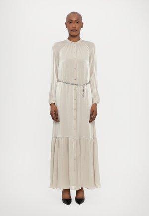 Robe longue en satin beige clair avec un devant à boutons, un col froncé, des manches longues et une jupe à volants. Ceinture en chaîne argentée incluse.