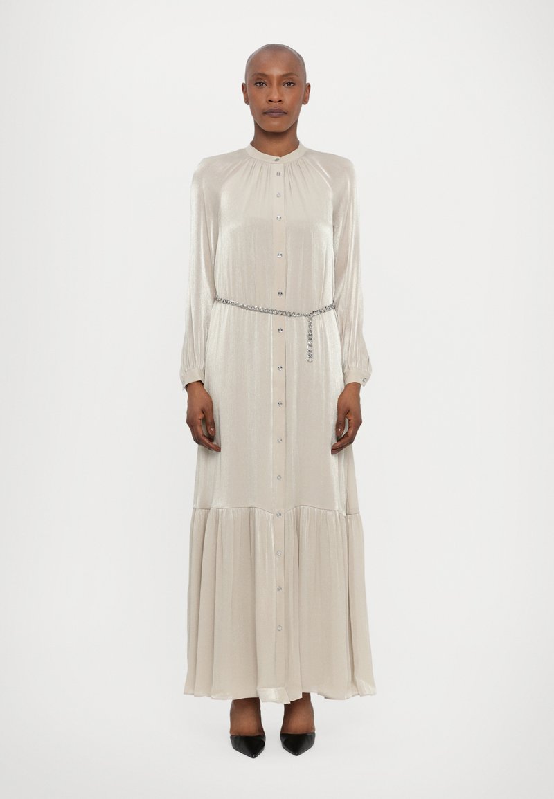 Robe longue en satin beige clair avec un devant à boutons, un col froncé, des manches longues et une jupe à volants. Ceinture en chaîne argentée incluse.