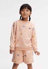Conjunto de sudadera y shorts en color rosa claro, fabricado en un tejido suave, que presenta estampados coloridos que incluyen la Torre Eiffel, animales y formas geométricas.