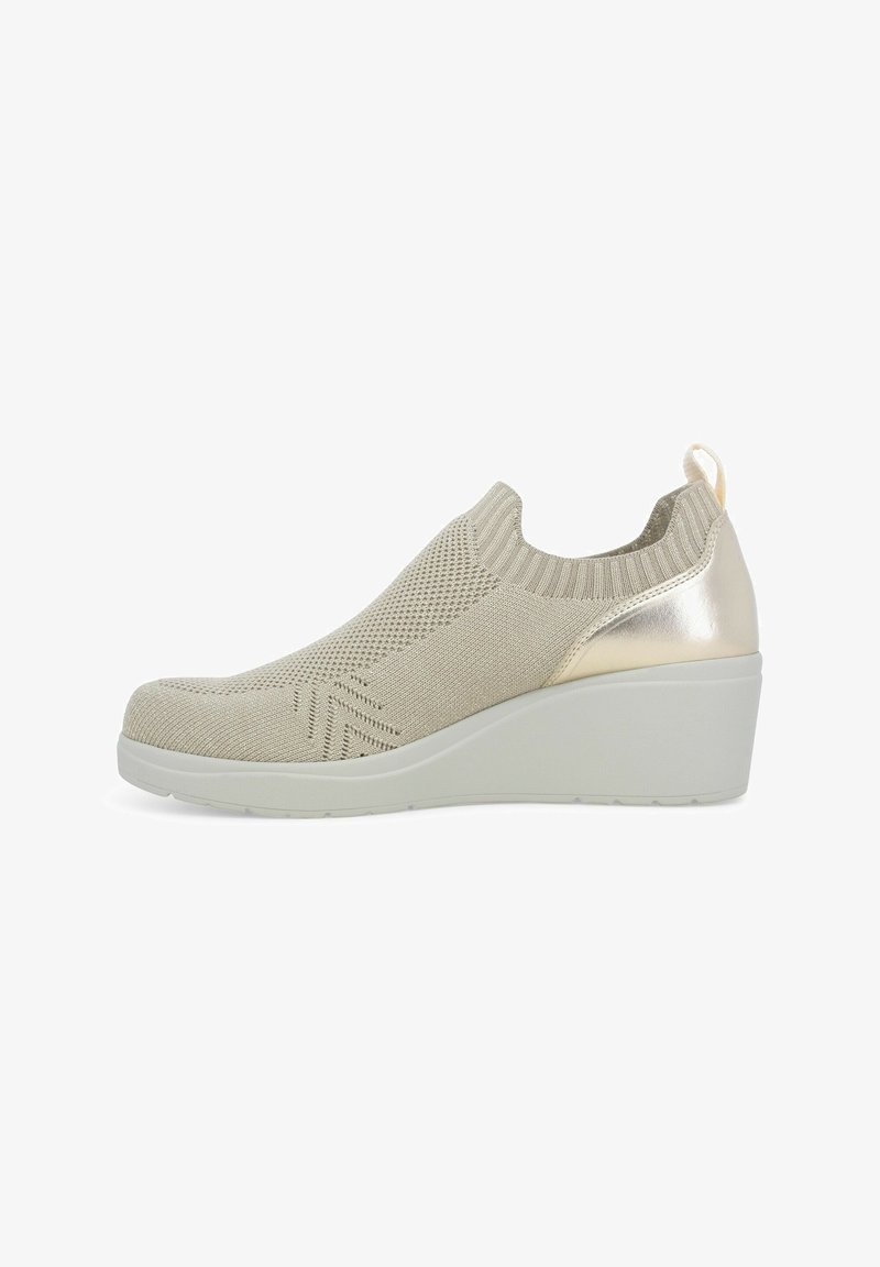 Scarpa slip-on in maglia beige con tacco a zeppa, caratterizzata da un motivo testurizzato e un accento metallico sul tacco. Suola flessibile e collare simile a una calza.