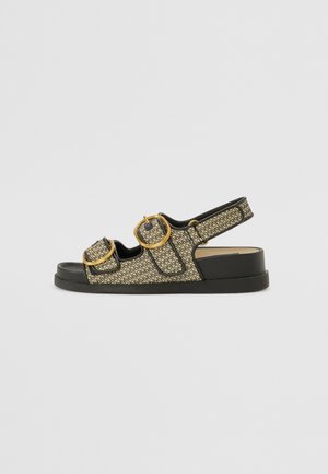 Black and gold patterned sandals featuring two large gold buckles, a flat sole, and an open back design for easy wear.