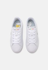 Sneakers bianchi con lacci, dotati di una tomaia in sintetico liscio e un logo Lacoste colorato. Presentano una soletta decorata con disegni di cartoni animati.