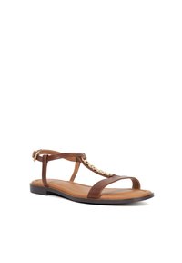 Brown leather sandal with a flat sole, featuring a T-strap design, chain detailing on the front, and an adjustable ankle strap.
