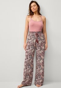 Lichtroze geribbelde tanktop met kantaanzet, gecombineerd met losse, gemusterde broek in bordeauxrood en crèmekleuren met een elastische tailleband.
