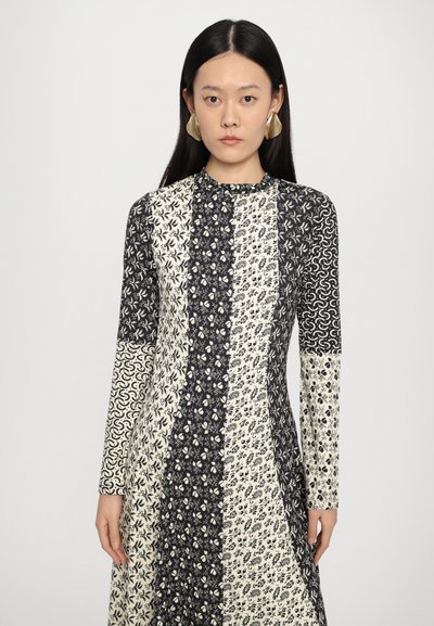 Pitkähihoinen mekko, jossa on musta ja kerma-valkoinen palapelin kuvio, kukkakuvioita ja abstrakteja muotoja, korkea kaulus ja slim fit.