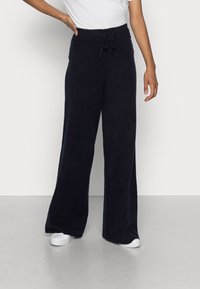 Marineblauwe wijde broek gemaakt van zacht materiaal, met een elastische tailleband met een trekkoord en zijnaadzakken.