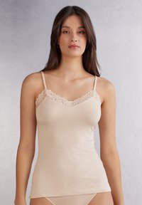 Beige tílko s krajkovým lemem podél výstřihu a tenkými, nastavitelnými ramínky. Měkký materiál s přiléhavým střihem a hladkou texturou.
