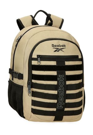 Mochila Reebok beige y negra con correas acolchadas, múltiples compartimentos con cremallera, correas horizontales negras y bolsillos laterales de malla.
