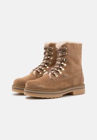 Stivaletti in suede marrone con fodera in pelliccia, chiusura a lacci con occhielli in metallo e suole in gomma spessa, progettati per il freddo.