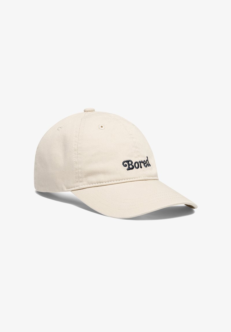 Bežinis medvilninis beisbolo kepuraitė su išlenktu kraštu ir juodu kursyvu išsiuvinėta "Bored" priekyje. Yra ventiliacijos angos viršuje.