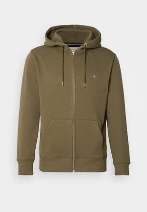 Olive green zip-up hoodie made of soft material, featuring a drawstring hood, front pockets, and a small logo on the chest.