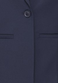 Námořnický blazer vyrobený z hladkého materiálu, s jedním černým knoflíkem, dvěma předními kapsami a klopovým límcem.