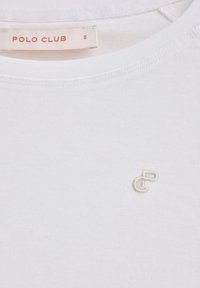 Vit bomull T-shirt med rund halsringning och en liten broderad logotyp i ljus beige på bröstet. Storleksmärkningen säger "S."