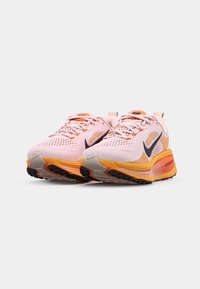 Zapatillas deportivas en color rosa y naranja con parte superior de malla, acentos en negro, suela acolchada y un prominente logo en forma de swoosh negro en los lados.