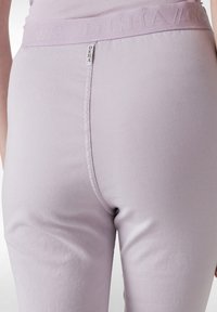 Lila leggings med en åtsittande design, elastisk midja med präglad logotyp och en slät, mjuk tygstruktur.