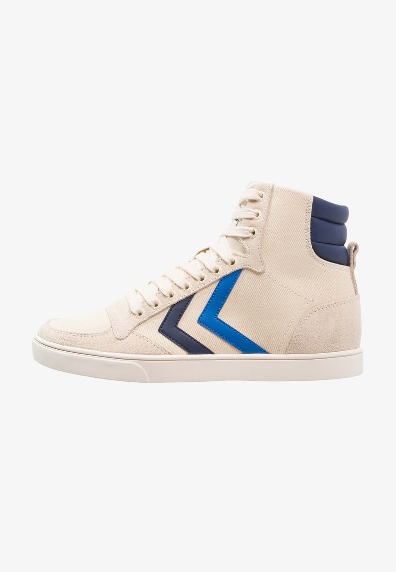 Baskets montantes beige avec lacets blancs, bandes chevron bleu marine et bleu sur le côté, et col de cheville rembourré bleu marine.