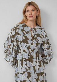 Maxikleid in Olivgrün mit weißen Blumenmustern, ausgestattet mit Rüschensäumen und einem Schlüsselloch-Ausschnitt.