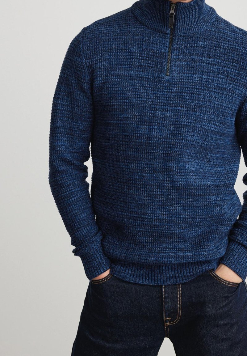Marineblauer Strickpullover mit hohem Kragen und Viertel-Reißverschluss-Design. Mit strukturiertem Stoff sowie gerippten Bündchen und Saum. Trägt man mit dunklen Jeans.