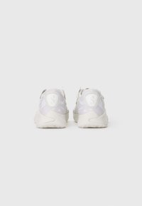 Pair of white athletic sneakers with thick soles, viewed from the back on a plain light gray background.