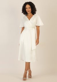 Weißes Wickelkleid mit kurzen, flatternden Ärmeln, einem Bindegürtel in der Taille und einem fließenden Rock. Hergestellt aus glattem Stoff mit leichtem Glanz und einer lockeren Passform.