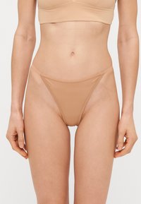 Nude bikini briefs with a minimal design, featuring thin side straps and a smooth, stretchy material for a seamless fit.