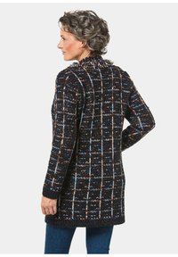 Schwarz-blaukariertes Strickcardigan mit strukturierter Oberfläche, lange Ärmel, einen Kragen und einen offenen Vorderteil.