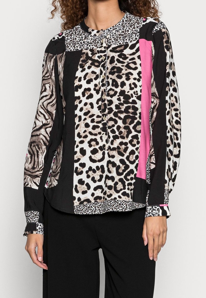 Blus med långa ärmar som har blandade djurmönster i svart, vitt och rosa, med en texturerad krage och knäppning fram.