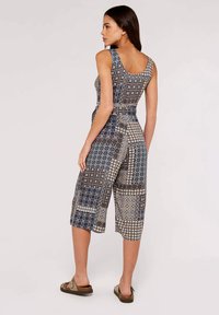Ärmelloser Jumpsuit in verschiedenen blau-weißen geometrischen Mustern, mit einem gerafften Bund und verkürzten Beinen. Texturiert Stoff.