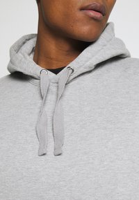 Hall hallipusa, millel on pehme kangasisu, kalasaba mustriga nöörid ja hõbedased silmad. Lähedalt vaadatuna krae ala.