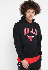 Sudadera negra de mezcla de algodón con capucha ajustable. Lleva la palabra "BULLS" y el logo en rojo en la parte delantera. Tiene un bolsillo tipo canguro en la parte delantera.