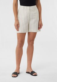 Hell gefärbte, gestreifte Shorts mit hohem Bund und entspannter Passform, kombiniert mit schwarzen, gewebten Slipsandalen.