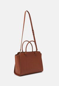 Sac à main en cuir marron avec deux poignées supérieures, une bandoulière détachable et un design structuré. Texture lisse avec peu de ferrures.