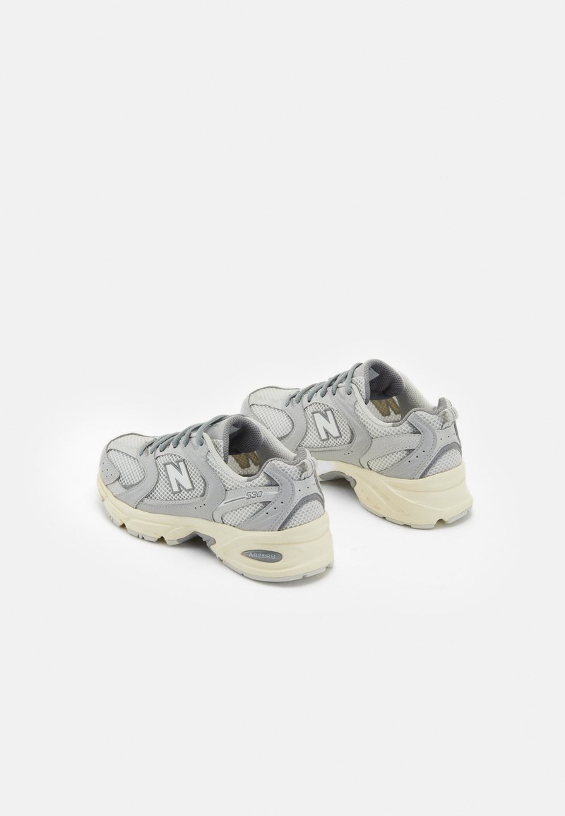 Baskets de sport gris en mesh avec semelle en caoutchouc, col rembourré et accents ton sur ton. Présente le logo "N" et le numéro de modèle "530" sur les côtés.