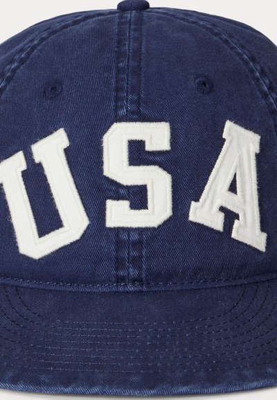 Casquette bleu marine avec des lettres blanches brodées "USA". Fabriquée en tissu texturé avec un visière incurvée et une fermeture à l'arrière ajustable.