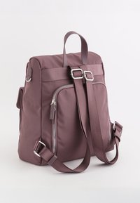 Lila Nylon-Rucksack mit doppelt verstellbaren Trägern, vorderer Reißverschlusstasche und Griff an der Oberseite. Verfügt über silberne Beschläge und Nahtdetails.
