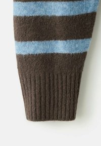 Cuff di un maglione lavorato a maglia a righe marroni e azzurre; texture a coste con righe orizzontali alternate. Tessuto in morbida lana, aspetto accogliente.