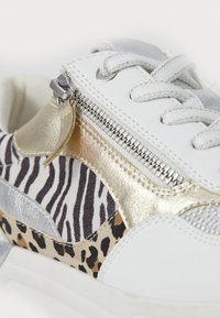 Sneakers con tomaia in pelle bianca, dettagli in oro e argento, e una combinazione di tessuto con stampa zebra e leopardata. Presentano un particolare con zip.