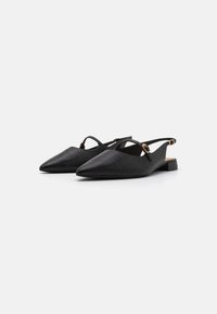 Des chaussures noires à bride arrière avec un bout pointu, fabriquées en matériau texturé, dotées de fines lanières et d'accents en métal doré.