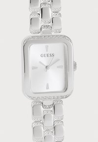 Silver rectangular watch with a minimalist white face, featuring a brand logo, four hour markers, and a beaded link bracelet design.
