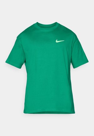 T-shirt en coton vert avec un col rond, des manches courtes et un petit logo Nike blanc sur la poitrine gauche. Texture lisse, coupe standard.