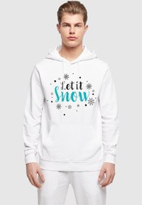 Hvid hættetrøje med frontlomme, med teksten "Let it Snow" trykt i teal og sort, omgivet af snefnug og prikker. Blød, afslappet design.