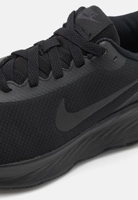 Sort atletiksko lavet af mesh og syntetiske materialer. Har en rund tå, tekstureret overdel og et sort Nike swoosh-logo.