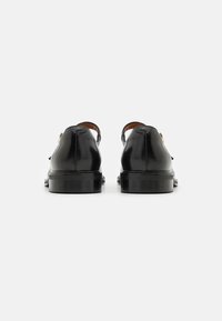 Zwarte leren schoenen met een gladde afwerking en een ronde neus. Voorzien van een lage hak en een subtiele bruine binnenvoering.