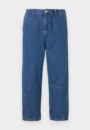 Jean en denim bleu à coupe décontractée, avec une jambe droite, des poches avant et des coutures décoratives. Pas de logos de marque visibles.