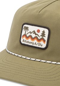 Green fabric cap with a white embroidered patch featuring mountains, sun, and trees. White and black accent stitching around the brim.