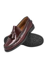 Mocasines de cuero burdeos con borlas, detalles de costura y suela de goma negra con textura circular para agarre y estabilidad.