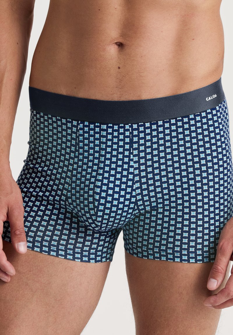 Blauwe gestreepte boxershorts met een donkere tailleband. De stof heeft een ruitpatroon in lichtblauwe tinten tegen een marineblauwe achtergrond.