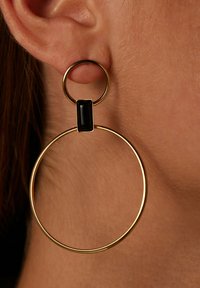 Gouden metalen oorbellen met een circulair hangoogdesign, voorzien van een zwarte rechthoekige stenen accent. Glad afwerkingsvlak, lichte uitstraling.