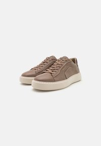 Braune Ledersneaker mit glatter Textur, runder Zehenpartie und niedrigem Profil. Ausgestattet mit flachen Schnürsenkeln und einer beigen Gummisohle.